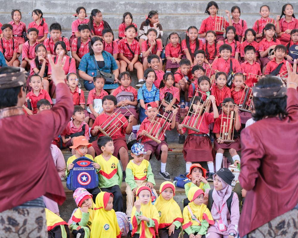 Siswa-siswi bermain angklung yang dibimbing oleh penari sanggar GWK di Amphitheater GWK Cultural Park
